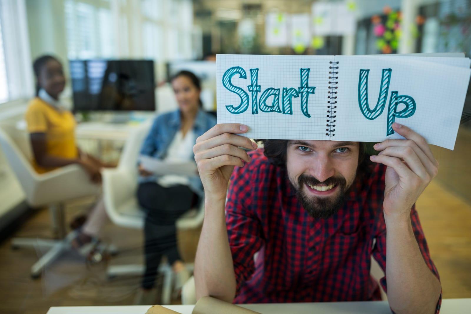 Founder holding up a notepad reading "Start Up"