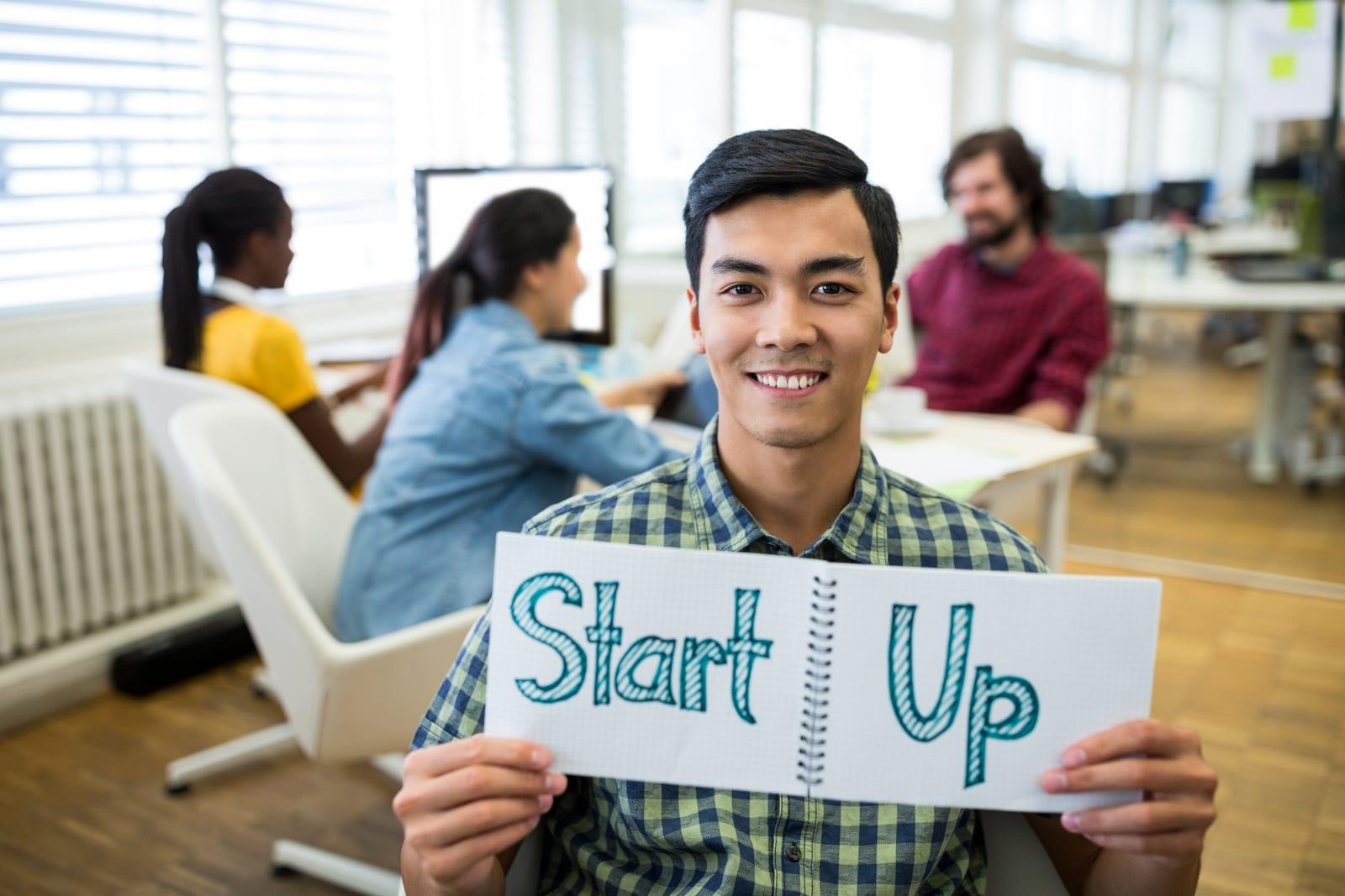 Founder holding up a notepad reading "Start Up"